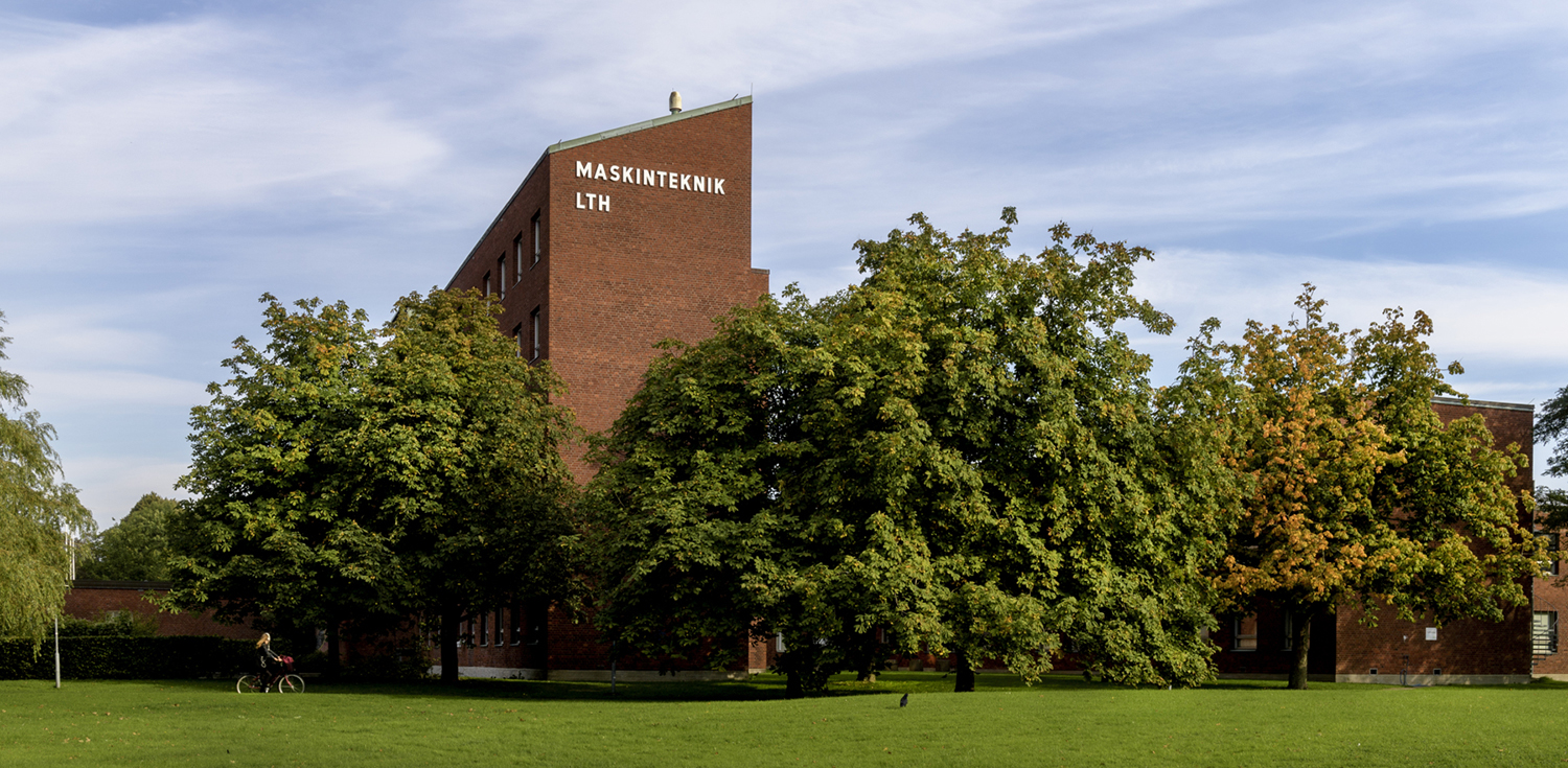 M-building. A brick building sticking out of trees. Photo.